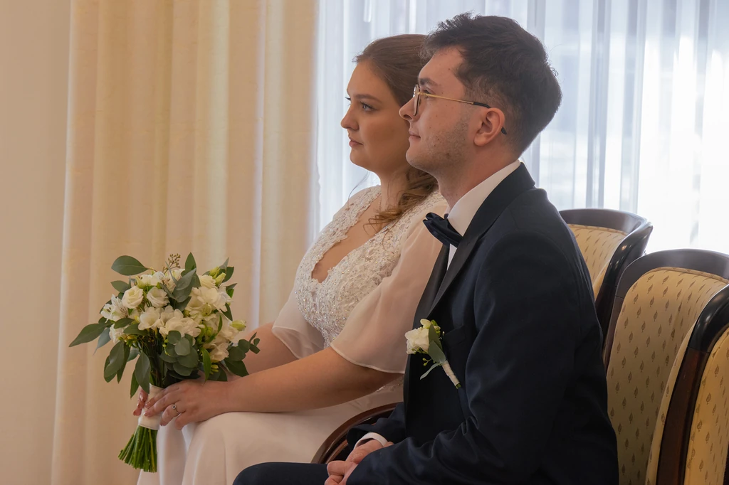 Nowożeńcy siedzą obok siebie podczas uroczystości