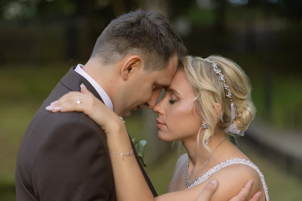 Para młoda zbliża do siebie czoła podczas sesji w plenerze